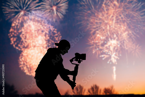 Silhouette of videographer is filming with cinema gimbal video dslr, professional video, videographer in events. Cinema lens on gimbal. Medium shot. Film or cameraman school. Space for text. Fireworks