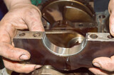 The mechanic holds the crankshaft mounting bracket in his hands