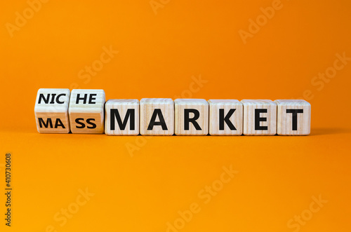 Mass or niche market symbol. Turned wooden cubes and changed words 'mass market' to 'niche market'. Beautiful orange background, copy space. Business and mass or niche market concept.
