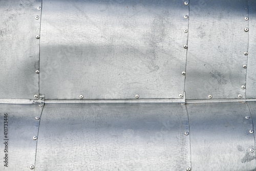 Sheet metal riveted, waved, weathered surface background image.