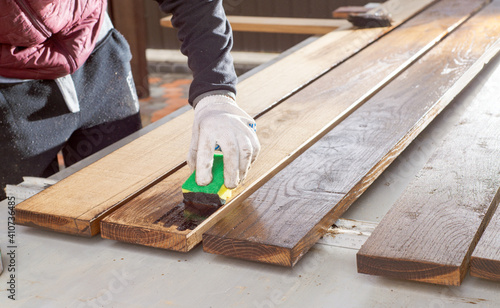 Brown color stain painting on wooden table or fence or wall, or flour, use for home decorated. House renovation. Half - painted surface. Hand holding brush. Background with copy space.