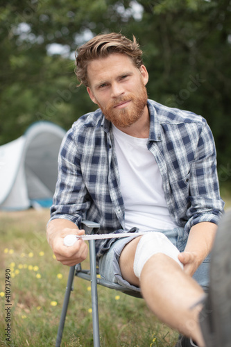man bandaging his knee while on camping holiday
