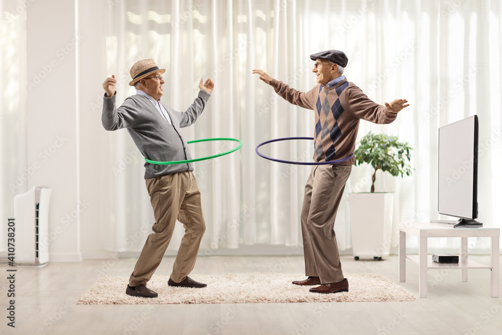 Funny elderly men spinning hula hoops inside a room