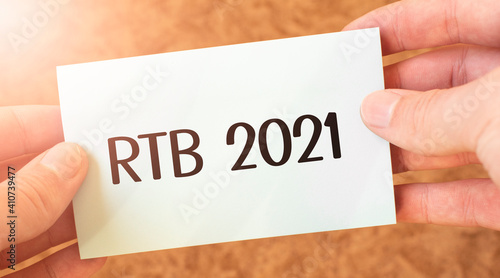 RTB 2021 word inscription on white card paper sheet in hands of a businessman. recap concept. red and white paper