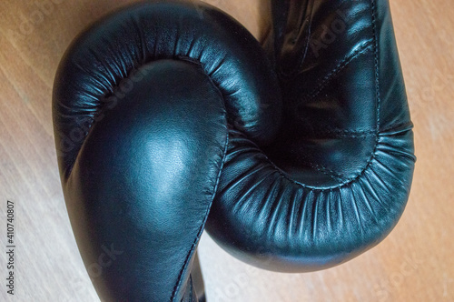 Two black boxing gloves on a wooden background