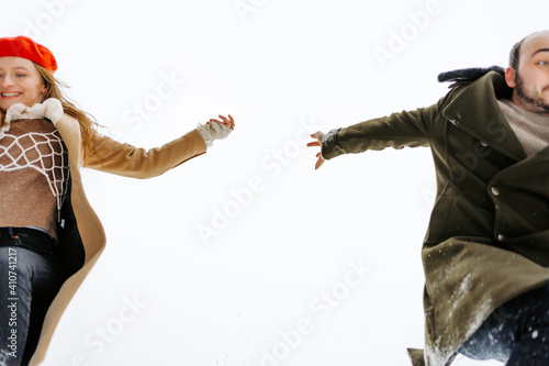 pareja feliz cogiéndose la mano y saltando en la nieve en un día de invierno photo