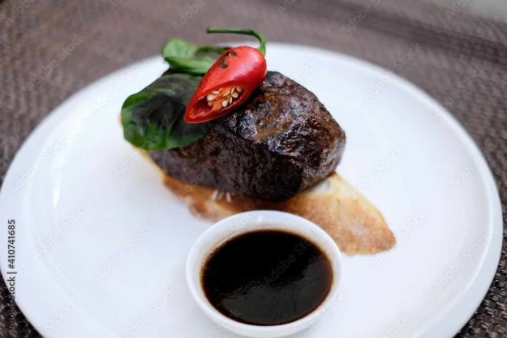 grilled beef fillet medallions on noodles with red hot chili pepper and salad leaf on white plate grilled beef fillet medallions on noodles with red hot chili pepper and salad leaf on white plate