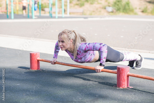 Young, athletic and beautiful girl doing push-ups on the sports ground