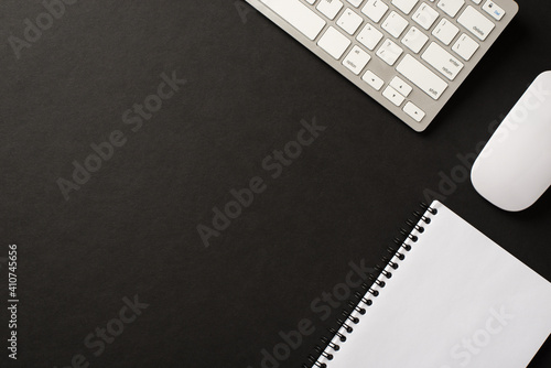 Flatlay photo of computer white accessories and open copybook with clear space isolated black color backdrop