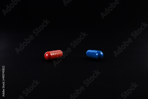 A red pill and a blue pill on black background. The concept of choice.