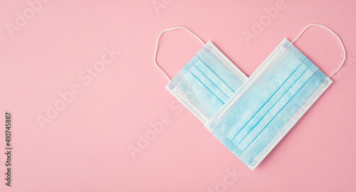 Charity and donation concept. Flat lay close up view photo of two blue medical masks making showing shape of heart isolated pastel color pink backdrop with copy blank space