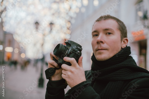 A man with a camera photographs the street of the old city in winter