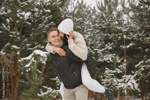 Lifestyle shot of couple walking in snowy forest. People spending winter vacation outdoors.