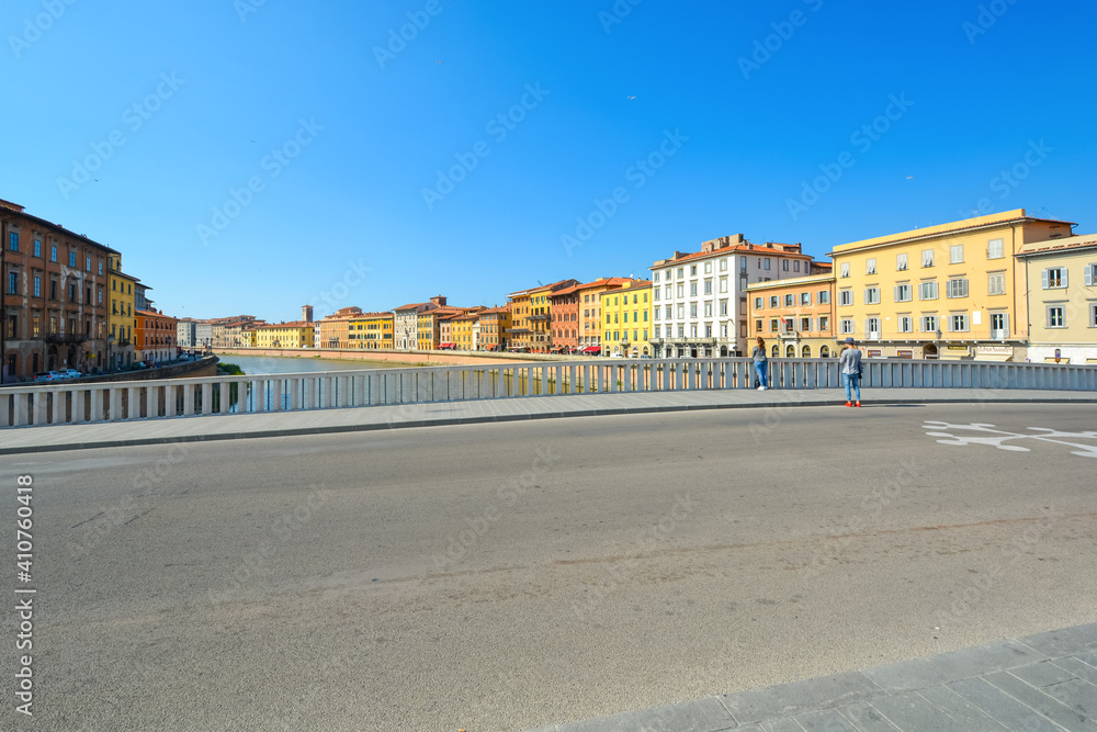 An unidentifiable young couple pauses on a bridge over the river Arno in the Tuscan city of Pisa, Italy.