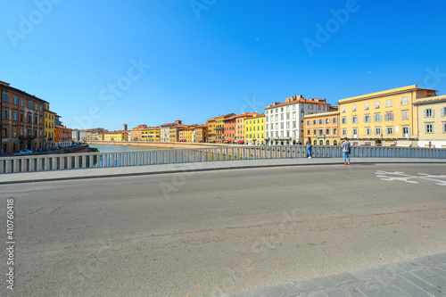 An unidentifiable young couple pauses on a bridge over the river Arno in the Tuscan city of Pisa, Italy.
