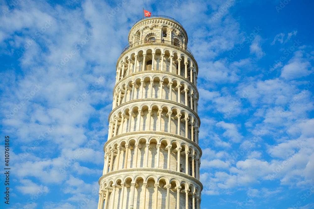 The top portion of the Leaning Tower of Pisa under a blue, partly cloudy sky in Pisa, Italy.