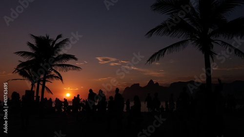 People enjoy the sunset surrounded by trees in Arpoador neighborhood, Rio de Janeiro photo