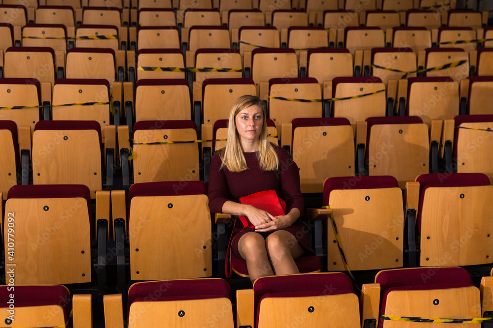 caucasian woman sitting at premiere in empty theatrical hall - obrazy, fototapety, plakaty 