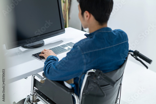 パソコンを使う男性身体障害者・車椅子