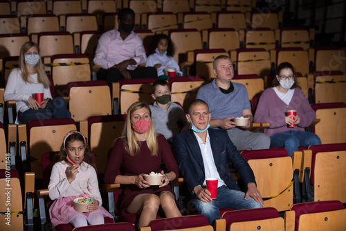 caucasian family sitting at premiere in cinema during pandemic photo