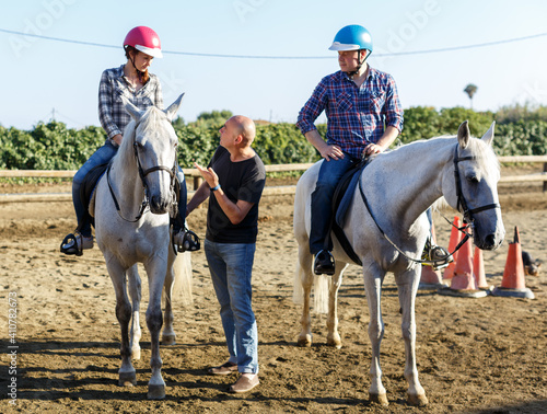 Trainer talking to woman while riding horse at farm outdoor © JackF