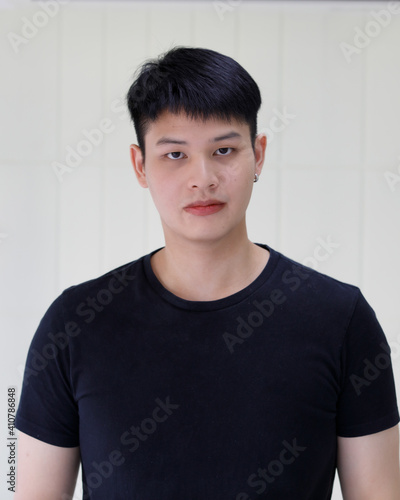 half body shot of young handsome and friendly Asian man wearing black t-shirt over white background. Concept of confident positive expression and happy people