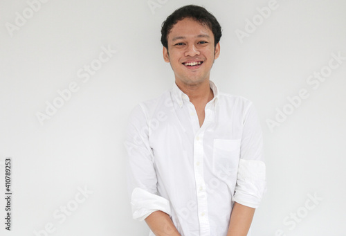 Portrait of Young funny Asian man with white shirt looking at camera and smiling happy expression © Reezky