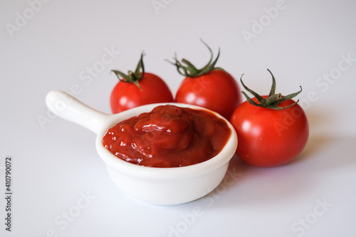 Fresh Otento sweet diamond tomatoes or cherry tomatoes and a white dipping bowl full of ketchup isolated on white background.