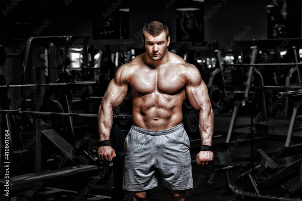 Athlete muscular brutal bodybuilder emotional posing in the gym