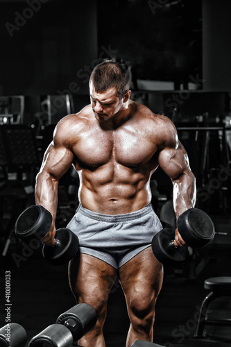 Athlete muscular bodybuilder in the gym training with dumbbells