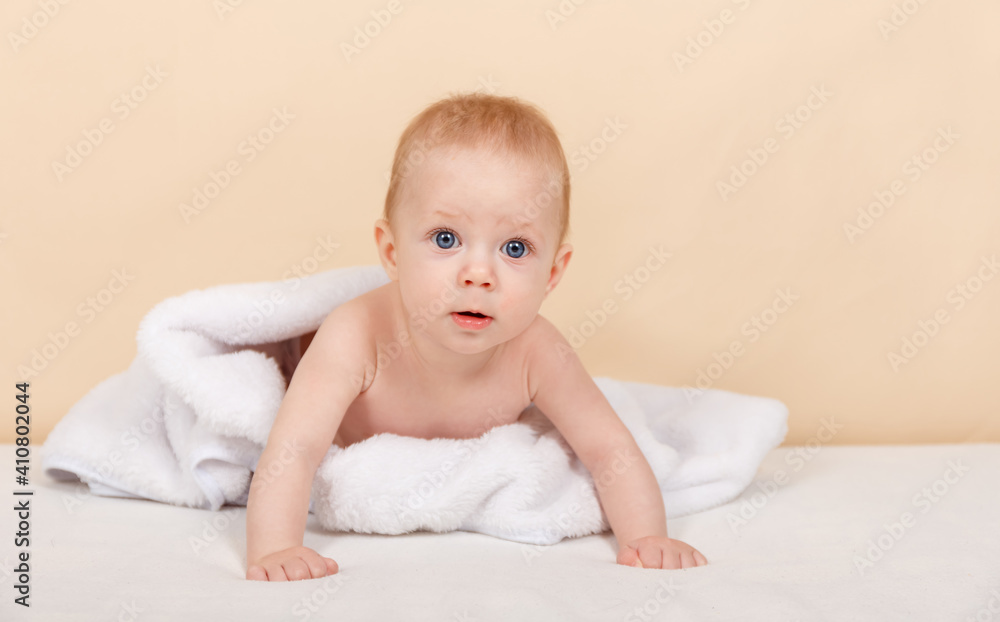 Funny newborn baby is resting in bed after a bath or shower. Portrait of smiling baby boy in white towel in bedroom at home. Textiles and bedding for children. Nursery, infancy concept. Copy space Funny newborn baby is resting in bed after a bath or shower. Portrait of smiling baby boy in white towel in bedroom at home. Textiles and bedding for children. Nursery, infancy concept. Copy space