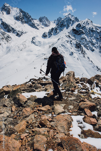 View of mountain peaks and rocks covered with snow around the clouds under the blue sky