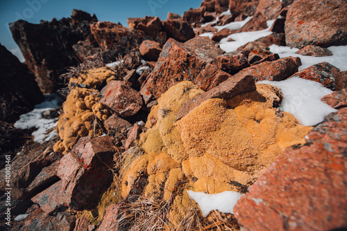 View of mountain peaks and rocks covered with snow around the clouds under the blue sky