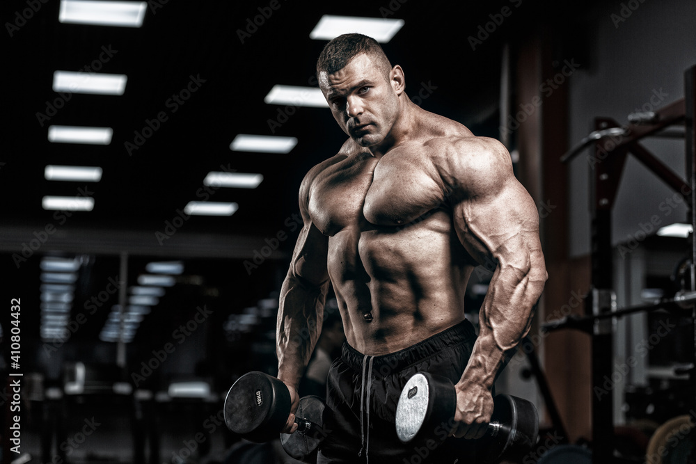 Muscular man bodybuilder training in gym and posing. Fit muscle guy workout with weights and barbell
 - obrazy, fototapety, plakaty 