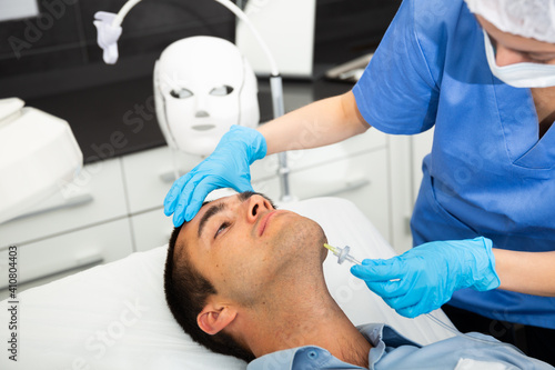 Male client getting carbon dioxide injections for face skin rejuvenation in clinic of aesthetic cosmetology.