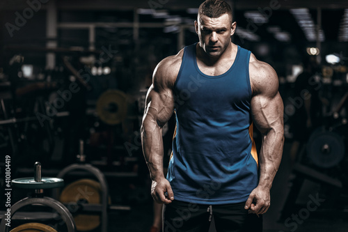 Obraz na plátně Muscular man bodybuilder training in gym and posing