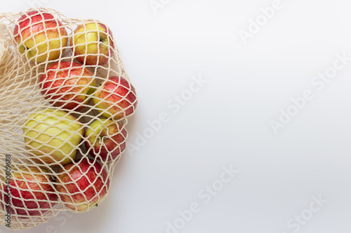 Apples in a biodegradable eco friendly string bag on white background. Photo with copy blank space.