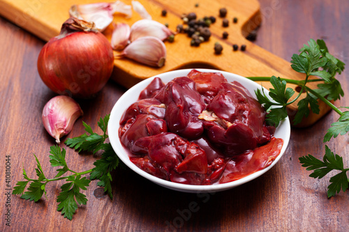 Fresh chicken liver on wooden background with parsley, garlic and onion