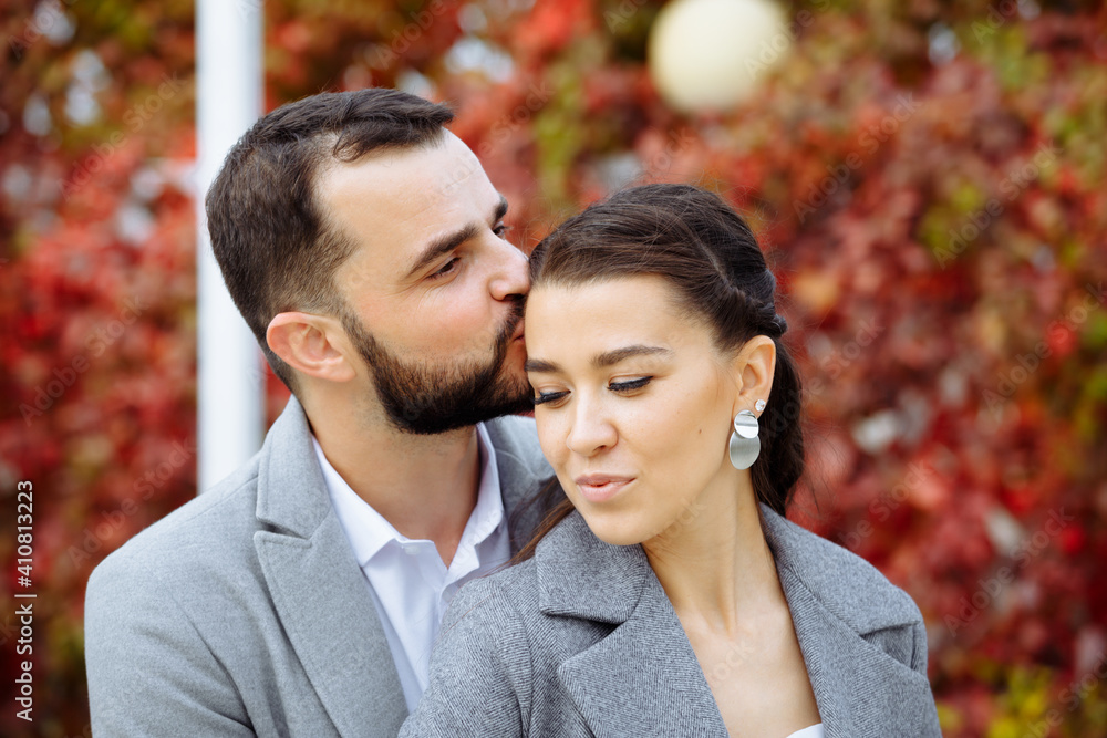 Stylish couple in gray coats gently hugging on the background of autumn leaves. Happy sensual wedding couple embracing. Romantic moments of newlyweds. Stylish couple in gray coats gently hugging on the background of autumn leaves. Happy sensual wedding couple embracing. Romantic moments of newlyweds.