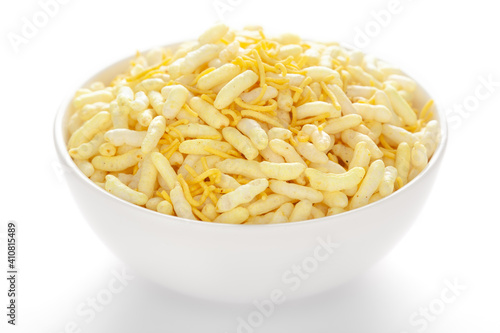Crunchy Lemon Bhel in a white ceramic  bowl made with Puffed Rice small besan sev. Pile of Indian spicy snacks (Namkeen)  under backlight side view 