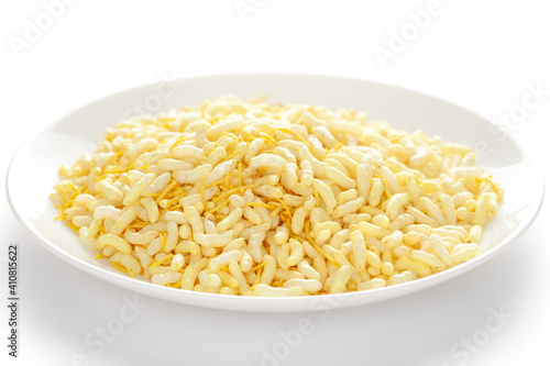 Crunchy Lemon Bhel in a white ceramic plate made with Puffed Rice small besan sev. Pile of Indian spicy snacks (Namkeen) under backlight side view 