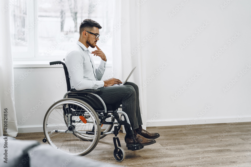 Businessman sitting in wheelchair and using laptop Businessman sitting in wheelchair and using laptop