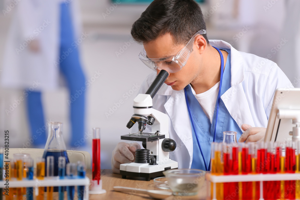 Male scientist working with microscope in laboratory Male scientist working with microscope in laboratory