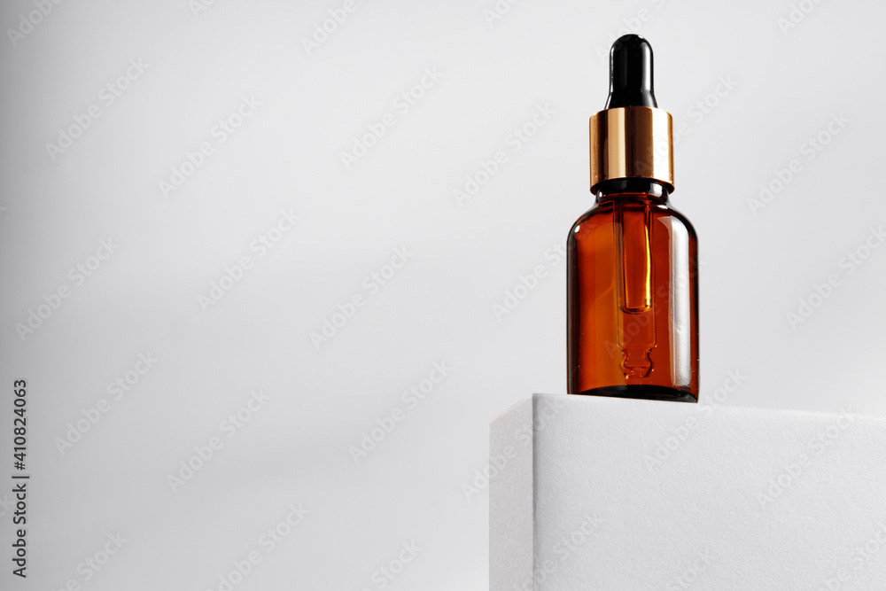 Essential oil bottle on gray block against gray background Essential oil bottle on gray block against gray background