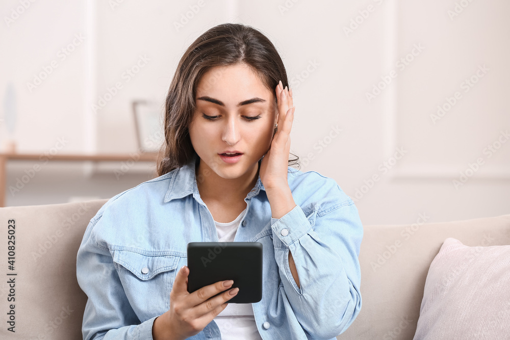 Beautiful young woman reading e-book at home Beautiful young woman reading e-book at home