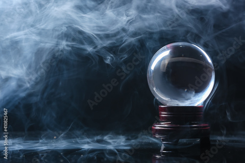 Crystal ball of fortune teller in smoke on dark background