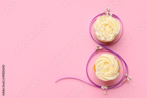 Figure 8 made of violet ribbon and cupcakes on color background. International Women's Day celebration