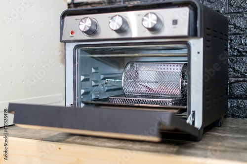 Electric oven cage or rotating basket inside air fryer oven. Modern technology kitchenware.