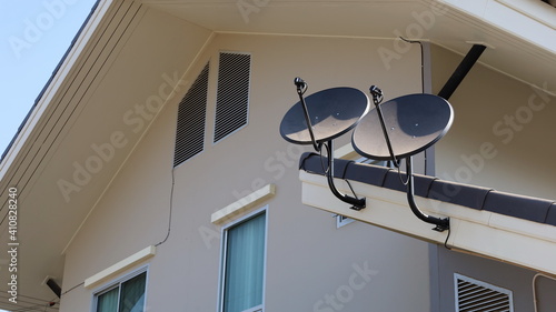 Two black satellite dishes on the roof. A solid dish used to receive a KU-Band satellite TV signal of 10 - 12 GHz frequency on a dwelling background with copy space. Selective focus photo