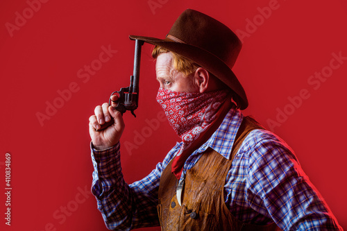 Portrait of man wearing cowboy hat, gun. Portrait of a cowboy. West, guns. Portrait of a cowboy. American bandit in mask, western man with hat. Portrait of cowboy in hat